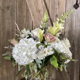 White hydrangeas and lilies with pale pink roses in a glass vase