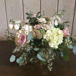 Low floral arrangement with pink roses, white hydrangeas, and greenery