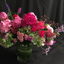 Pink and purple floral arrangement in a green glass vase