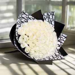 Bouquet of white roses wrapped in black-and-white patterned paper