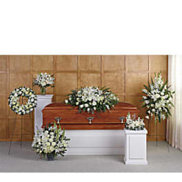 Funeral casket surrounded by white floral sprays and wreaths