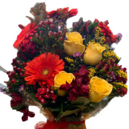 Bouquet of yellow roses and red gerbera daisies in a wrapped vase