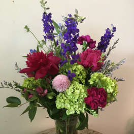 Mixed bouquet in a clear glass vase with purple, pink, and green flowers