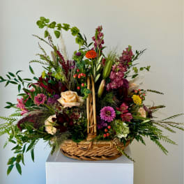 Mixed flower arrangement in a wicker basket with pink, purple, and peach blooms