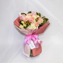 Pink and white bouquet of roses and carnations in wrapping with a ribbon