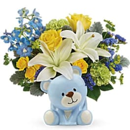Bouquet of white lilies, yellow roses, and blue flowers with a teddy bear vase