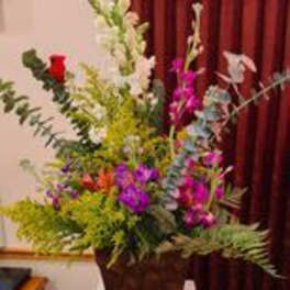 Tall mixed floral arrangement in a dark urn on a table