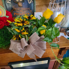 Yellow roses and black-eyed Susans in a burlap-wrapped container with a bow