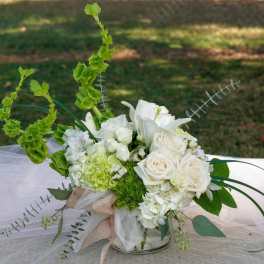 White floral arrangement with roses and lilies in a glass vase