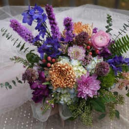 Colorful bouquet with purple, pink, and orange flowers on white tulle