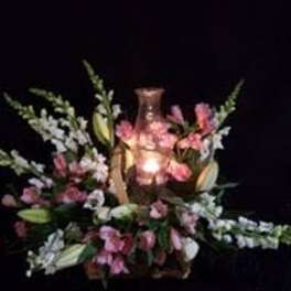 Pink and white floral arrangement around a lit glass candle holder