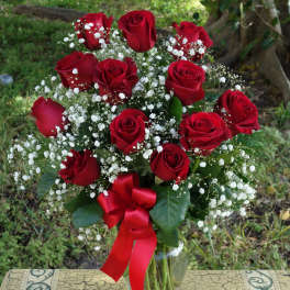Red roses with baby's breath in a glass vase and red ribbon
