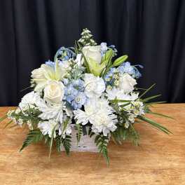 White and pale blue floral arrangement in a white basket