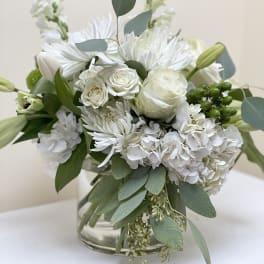 White floral bouquet in a clear glass vase with eucalyptus