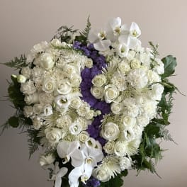 Large white funeral spray with roses and orchids on a stand