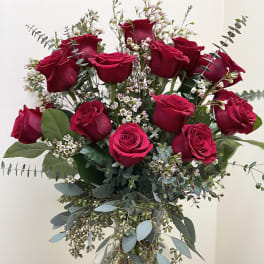 Bouquet of red roses with white filler flowers in a clear glass vase