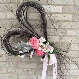 Heart-shaped twig wreath with pink roses and a pale ribbon