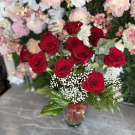 Red roses arranged in a glass vase with white filler flowers