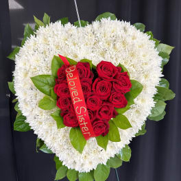 Heart-shaped white chrysanthemum wreath with red roses and a ribbon