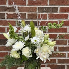 White flowers arranged in a glass vase with greenery and branches