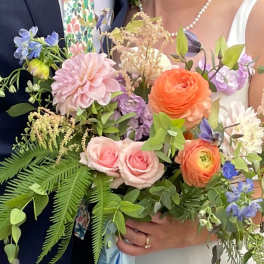 Bride and groom holding pastel wedding bouquets with roses and ranunculus