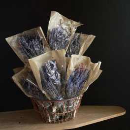 Bundles of dried lavender in paper sleeves inside a wire basket