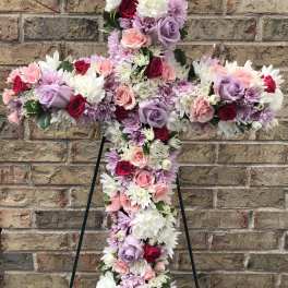 Cross-shaped floral tribute with pink, white, lavender, and red blooms