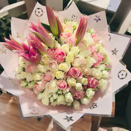 Bouquet of pink and white roses with pink lilies in pastel wrapping