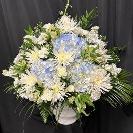 White and pale blue floral arrangement in a white vase