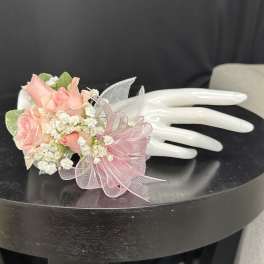 Pink rose corsage with white baby's breath on a white mannequin hand