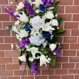 Standing floral spray with white lilies, blue roses, and purple blooms