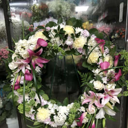 Large floral wreath with pink lilies and white blooms on a stand
