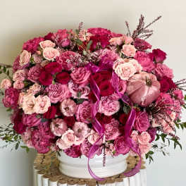 Large pink and magenta rose arrangement in a white vase
