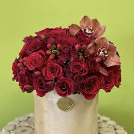 Red rose arrangement in a beige hatbox with two orchid blooms