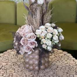 Pink and white rose arrangement in a textured vase with dried grasses