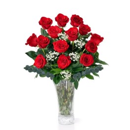 Red roses arranged in a clear glass vase with white filler flowers