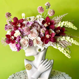 Floral arrangement in a white bust vase with pink and burgundy blooms