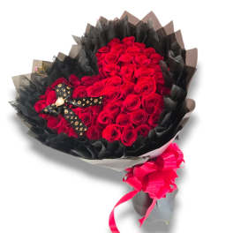 Bouquet of red roses wrapped in black paper with a pink ribbon