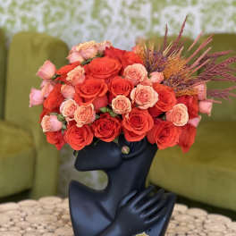 Red and peach roses arranged in a black sculptural vase