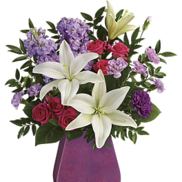 Bouquet of white lilies, pink roses, and purple flowers in a glittery vase