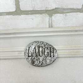 Decorative stone with the word LAUGH on a white surface