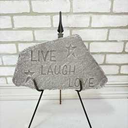 Decorative stone sign on a metal stand with the words Live Laugh Love
