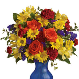 Colorful bouquet of roses, daisies, and carnations in a blue vase