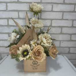 Cream and tan floral arrangement in a wooden cigar box