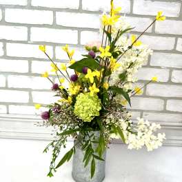 Tall mixed flower arrangement in a metal vase with yellow and white blooms