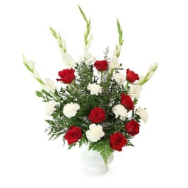 Red and white rose arrangement in a white vase