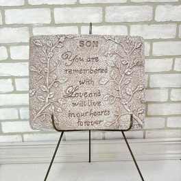 Memorial plaque on a metal stand with engraved text and leaf design