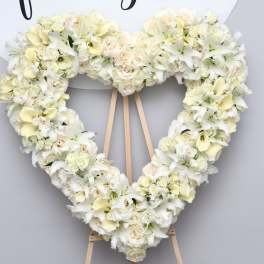 Heart-shaped white floral wreath on a wooden easel