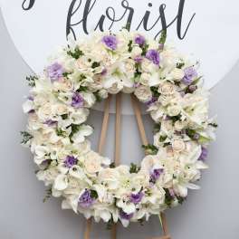 Large floral wreath of white and pale lavender flowers on an easel