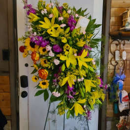 Large standing floral spray with yellow lilies and purple flowers